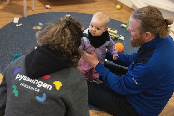 pappa, baby och pedagog sitter på golvet och pratar