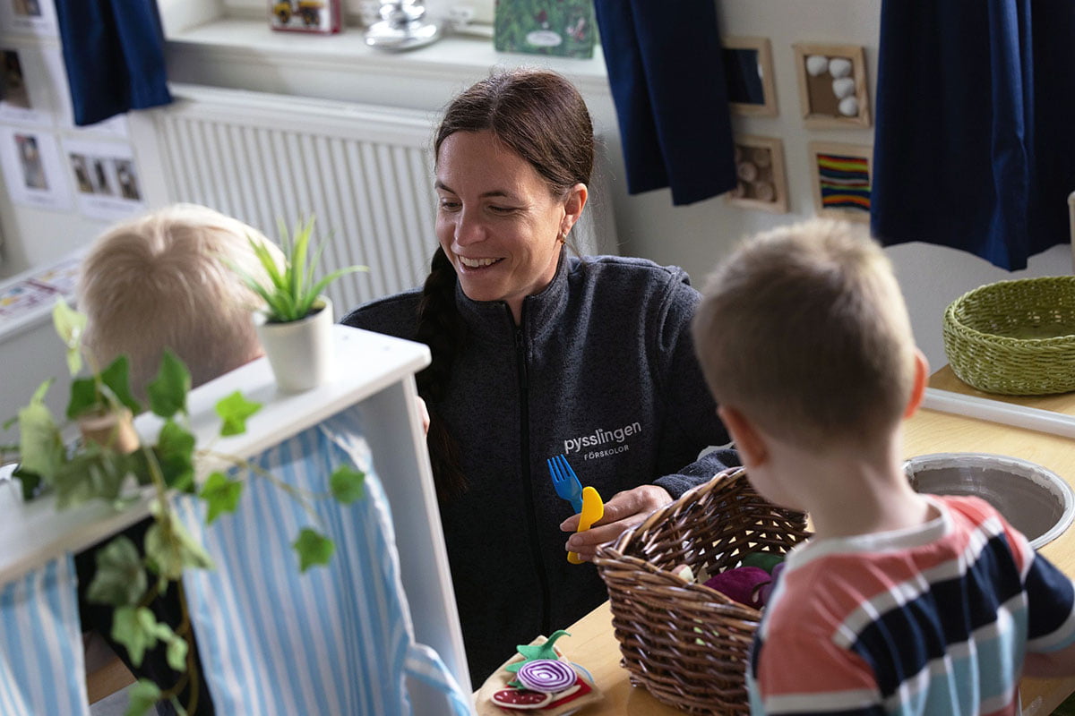 leende pedagog sitter på golvet och leker med barn