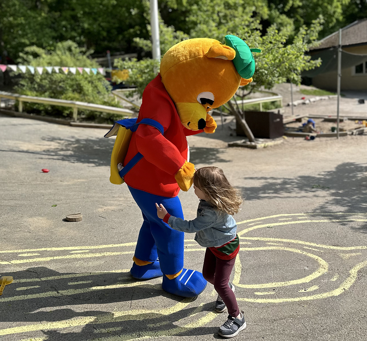 Maskoten Pyss dansar med ett barn