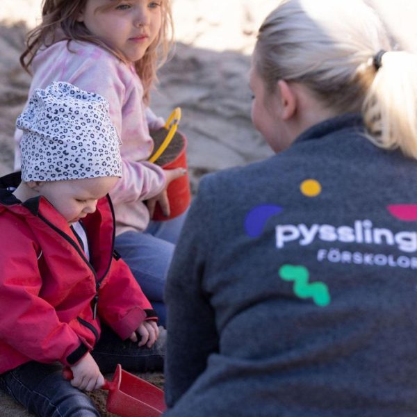 barn och pedagog leker i sandlådan