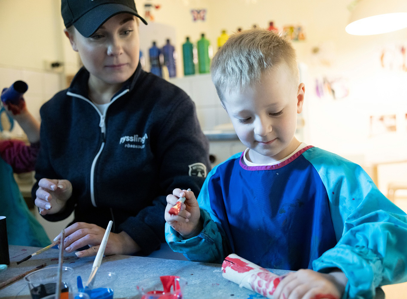 pedagog och barn sitter tillsammans och skapar