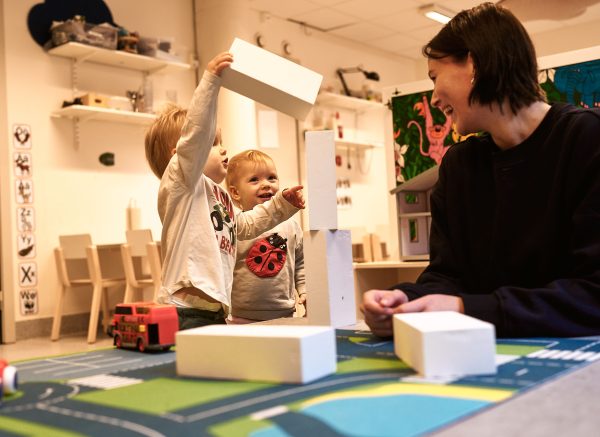 barn leker med klossar med en vuxen som ser på