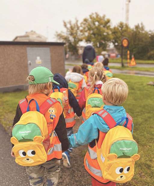 förskolebarn med ryggsäckar som går två och två i led