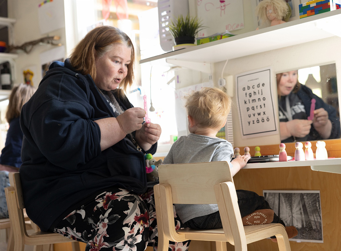 pedagog och barn sitter och interagerar på förskolan